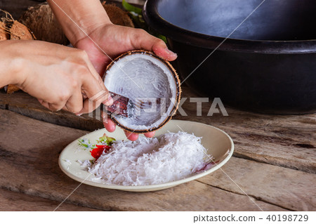Woman using hand scraping coconut put the utensil. Woman using hand scraping coconut put the utensil. 40198729