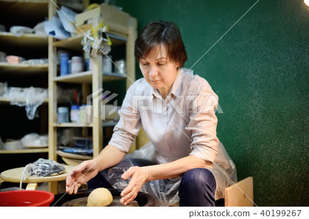 Middle age woman making clay object. The sculptor during work in pottery workshop 40199267