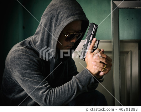 Hooded man with a gun in the dark room Hooded man with a gun in the dark room 40201888
