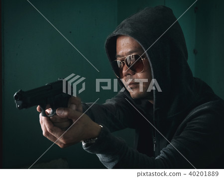 Hooded man with a gun in the dark room 40201889