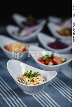 Salads in white plates on the table. Salad of Korean carrots, cucumber and cheese in the foreground 40202155
