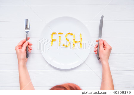 female hands under plate with Cod Liver Oil Capsul female hands under plate with Cod Liver Oil Capsul 40209379