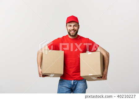 Delivery Concept: Smiling handsome caucasian delivery man holding a paper box. Isolated over grey 40210227