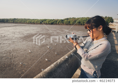 Asian woman talking picture of seascape and birds. 40214073