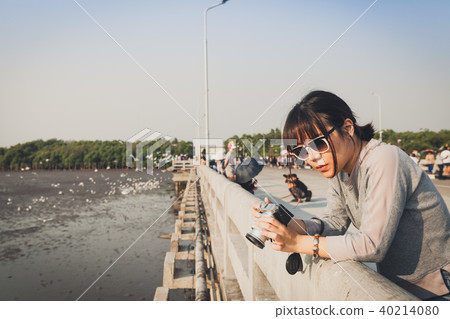 Asian woman with camera standing on the bridge. Asian woman with camera standing on the bridge. 40214080