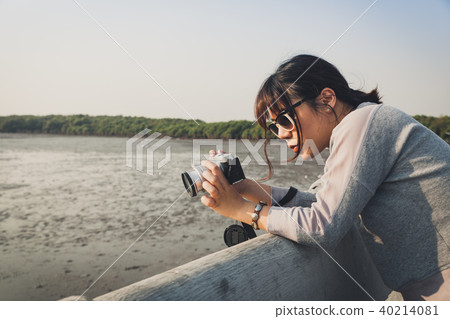 Asian woman talking picture of seascape and birds. 40214081