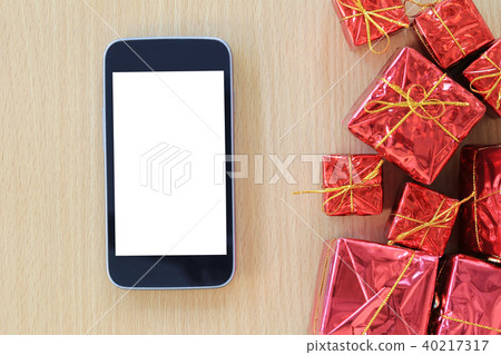 Empty Screen of Smartphone and red gift box are placed on a brown wooden floor. Empty Screen of Smartphone and red gift box are placed on a brown wooden floor. 40217317