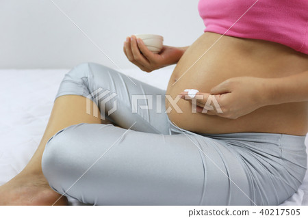 Pregnant mom is applying skin cream on the stomach. 40217505