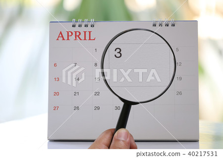Magnifying glass in hand on calendar you can look third day of month,Focus number three in April. Magnifying glass in hand on calendar you can look third day of month,Focus number three in April. 40217531
