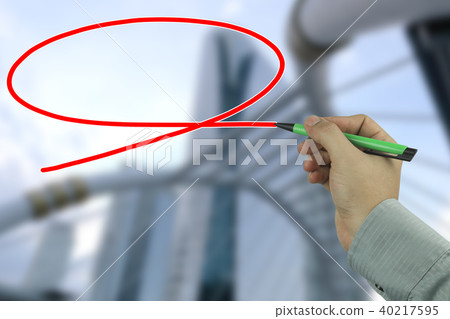 Hand of a businessman holding a green pen writing a message box on blur business building background. Hand of a businessman holding a green pen writing a message box on blur business building background. 40217595