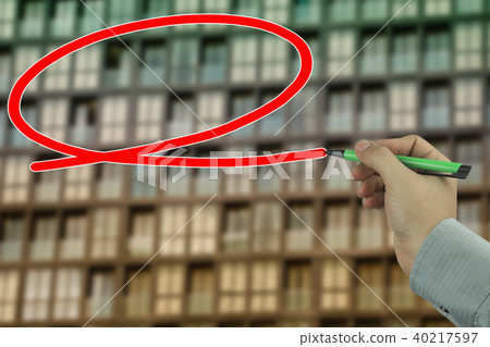 Hand of a businessman holding a green pen writing a message box on blur sky and building background. 40217597