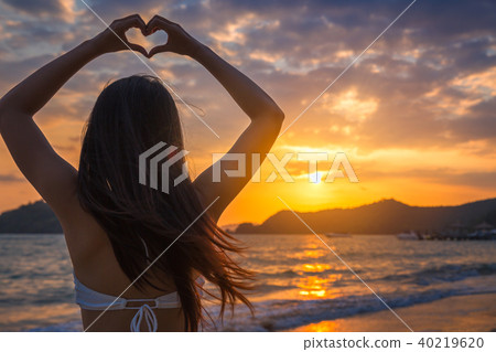 Woman with bikini making heart sign on beach Woman with bikini making heart sign on beach 40219620