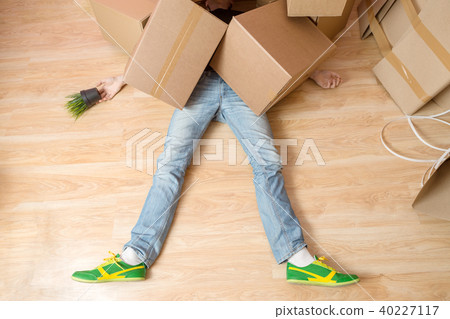 Photo of man in jeans and sneakers lying under cardboard boxes Photo of man in jeans and sneakers lying under cardboard boxes 40227117