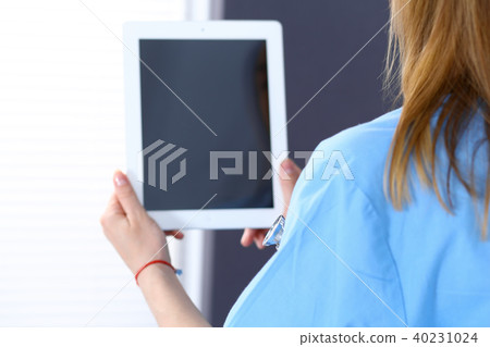 Woman doctor using tablet computer while standing straight in hospital office, closeup. Healthcare Woman doctor using tablet computer while standing straight in hospital office, closeup. Healthcare 40231024