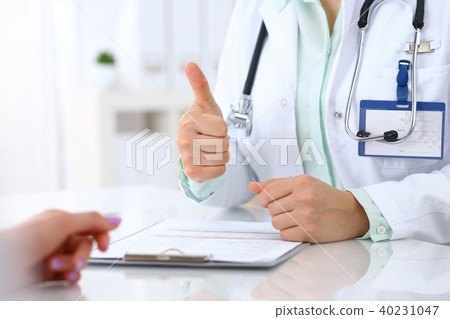 Doctor showing Ok sign  and thumb up to patient while sitting at the desk in hospital office, closeu 40231047