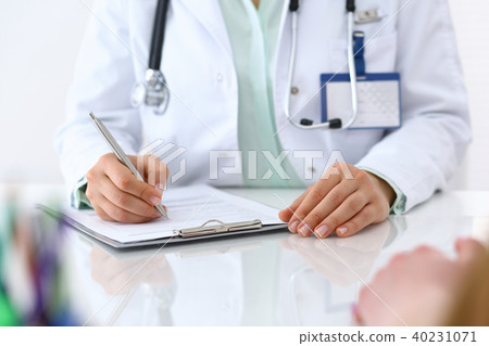 Female doctor filling up an application form while consulting patient. Just hands. Medicine an Female doctor filling up an application form while consulting patient. Just hands. Medicine an 40231071