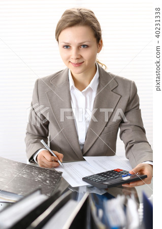 Portrait of female bookkeeper or financial inspector making report, calculating or checking balanc Portrait of female bookkeeper or financial inspector making report, calculating or checking balanc 40231338