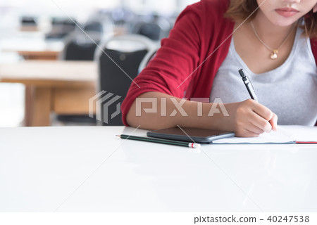 Asian woman writing at library. Asian woman writing at library. 40247538