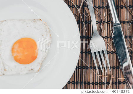 Fried egg in white plate and fork on wooden table 40248271