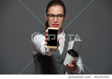 Pretty female office worker showing smartphone 40256364