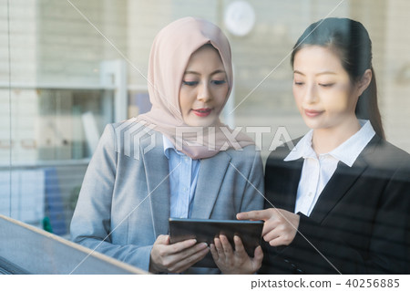 Two Asian businesswomen using a tablet. Two Asian businesswomen using a tablet. 40256885