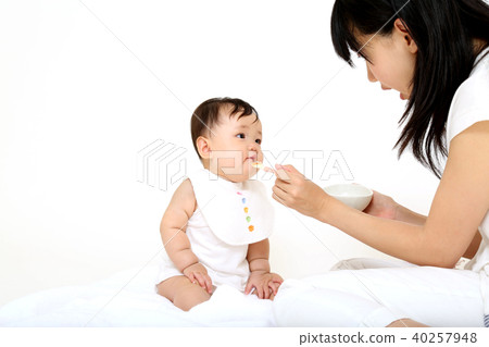 Young mother letting baby eat baby food 40257948