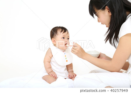 Young mother letting baby eat baby food 40257949