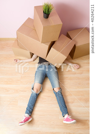 Photo of woman in jeans lying under cardboard boxes Photo of woman in jeans lying under cardboard boxes 40264211