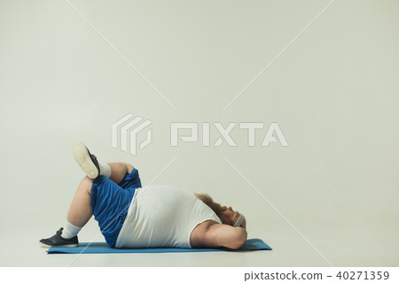 Sluggish thick guy relaxing on sports carpet Sluggish thick guy relaxing on sports carpet 40271359