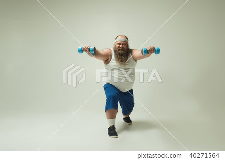 Strained fat man lifting dumbbells while squatting 40271564