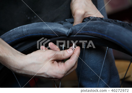 Picture of man repairing wheel of bicycle. 40272972