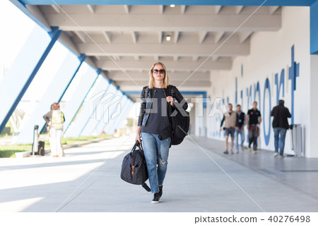 Portrait of young cheerful female traveler wearing casual clothes carrying heavy backpack and 40276498
