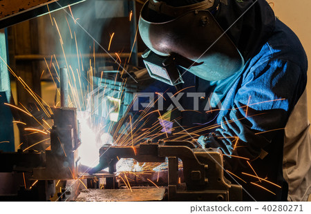 Worker is welding automotive part in car factory 40280271