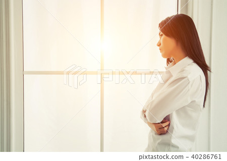 Beautiful young woman looking out in window at home 40286761