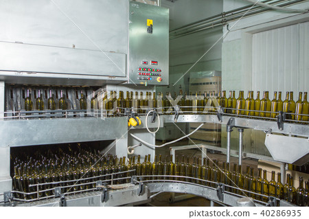 Unlabeled glass bottles in bottling machine at modern winery Unlabeled glass bottles in bottling machine at modern winery 40286935