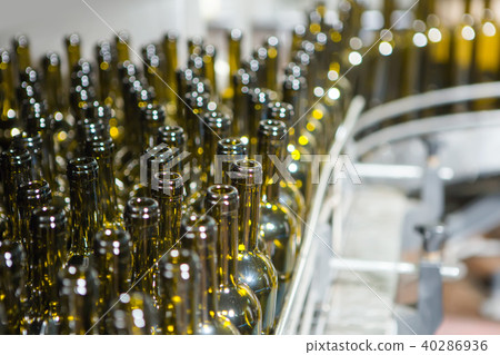 Unlabeled glass bottles in bottling machine at modern winery 40286936