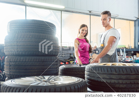 Handsome auto mechanic helping a customer to choose from various tires Handsome auto mechanic helping a customer to choose from various tires 40287830
