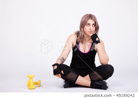 Fit woman in sport clothes lying down with two dumbbells aside her 40289242