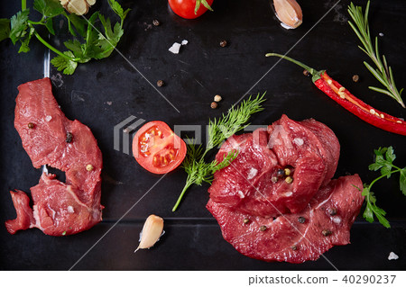 Flat lay of raw beefsteak with vegetables, herbs and spicies on metal tray, close-up, selective Flat lay of raw beefsteak with vegetables, herbs and spicies on metal tray, close-up, selective 40290237