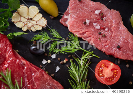 Flat lay of raw beefsteak with vegetables, herbs and spicies on metal tray, close-up, selective 40290256
