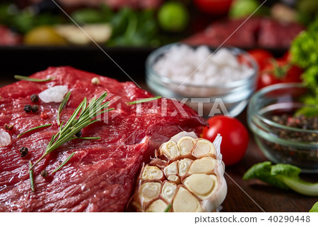 Still life of raw beef meat with vegetables on wooden plate over vintage background, top view Still life of raw beef meat with vegetables on wooden plate over vintage background, top view 40290448