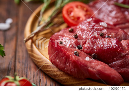 Still life of raw beef meat with vegetables on wooden plate over vintage background, top view Still life of raw beef meat with vegetables on wooden plate over vintage background, top view 40290451