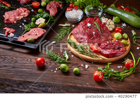 Still life of raw beef meat with vegetables on wooden plate over vintage background, top view 40290477