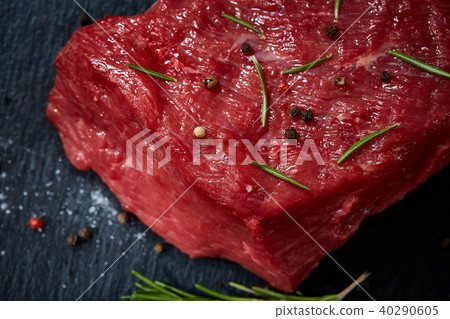 Raw meat beef steaks on black slate board with spices and rosemary over wooden background, copy 40290605