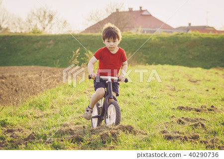 Boy rides a balance bike in the countryside Boy rides a balance bike in the countryside 40290736