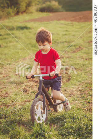 Boy rides a balance bike in the countryside Boy rides a balance bike in the countryside 40290737