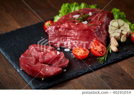 Composition of raw beefsteak on slate board with vegetables and seasoning, selective focus, close-up 40291059