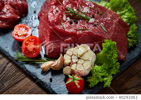 Composition of raw beefsteak on slate board with vegetables and seasoning, selective focus, close-up 40291061