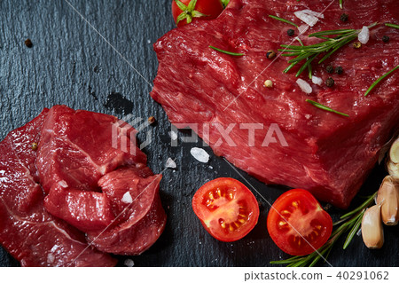 Composition of raw beefsteak on slate board with vegetables and seasoning, selective focus, close-up 40291062