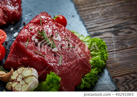 Composition of raw beefsteak on slate board with vegetables and seasoning, selective focus, close-up 40291065
